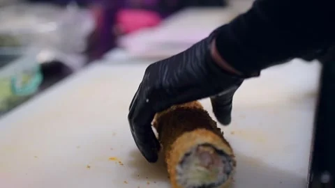Chef cutting a fried roll on a white cutting board, gloved hand holding the food Video stock 293483439