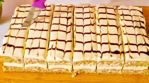 Chef cutting a glazed layered cake into rectangular slices on a wooden board Video stock 327259005