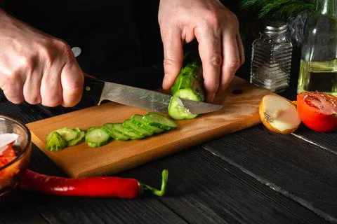 Chef cutting a green cucumber in kitchen in the restaurant. Making delicious Stock Photos