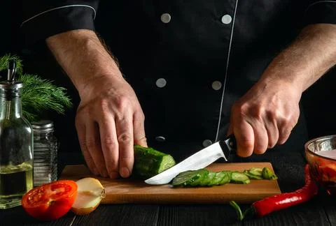 Chef cutting green cucumber in kitchen in the restaurant. Making delicious Stock Photos