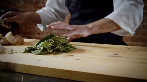 The chef cutting green leaves of basil up on a chopping board in the kitchen. 4K Stock Footage 78422290