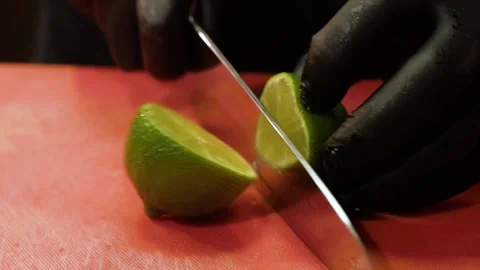 Chef cutting green lime in two pieces with knife on cutting board table.  Stock Footage 147599028