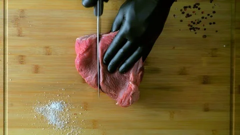 The chef is cutting meat. Man in black gloves cooks on a cutting board. Vídeo Stock 112002701