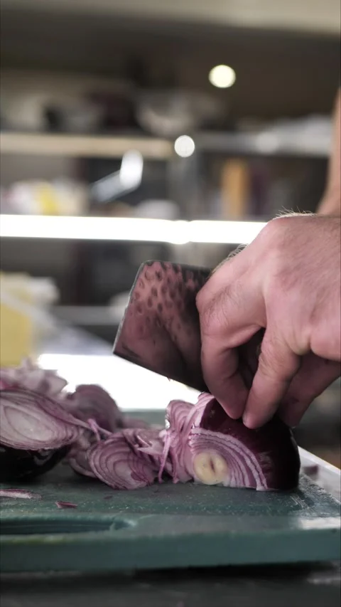 Chef cutting onion on cutting board in restaurant kitchen Stock Footage 306211098
