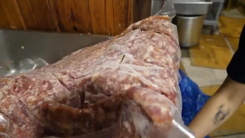 Chef cutting open a large plastic bag filled with fresh raw minced meat in a com 스톡 동영상 343588292