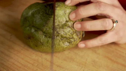 Chef cutting open a soft, ripe, black zapote in slow motion with a chef's knife Video stock 123470925