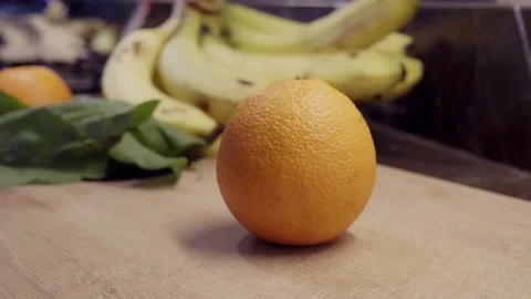 A chef cutting orange on halves on cutting board Stock Footage 92845485
