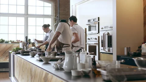 Chef cutting potatos with a mandolin while other chefs cook beside him in interi Stock Footage 199462807