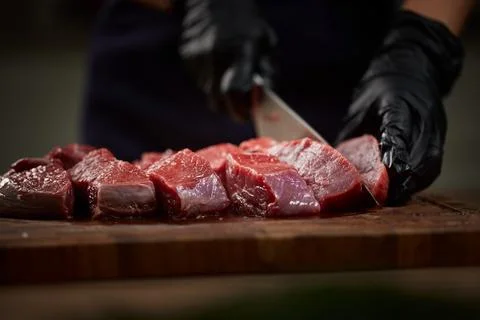 Chef cutting raw beef steak on wooden board Stock Photos