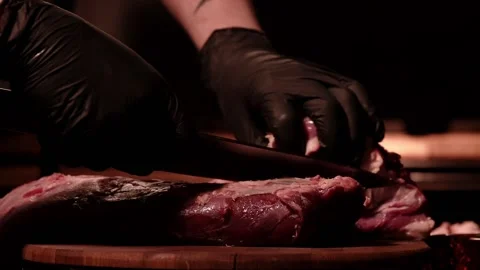 Chef is cutting raw beef tenderloin on a wooden board. Marbled meat. Dark Stock Footage 152833318