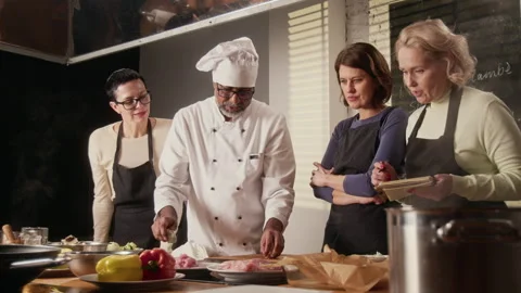 Chef Cutting Raw Meat Among Group of Women at Cooking Master Class Stock Footage 332570478