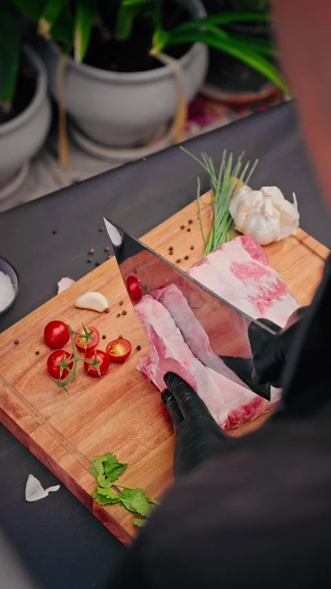 Chef cutting raw pork ribs with cleaver on wooden board Stock Footage 314606752