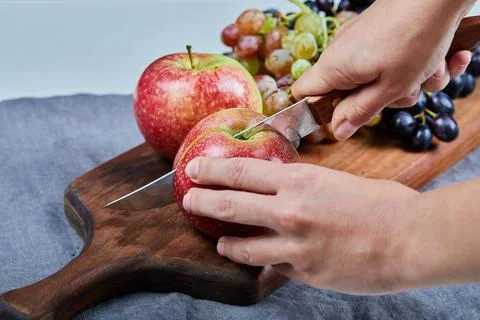 Chef cutting a red apple with a knife on the board Stock Photos