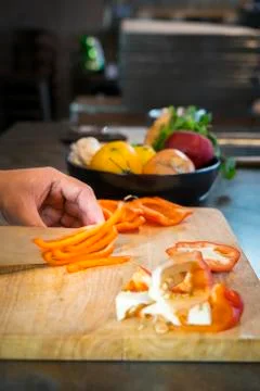 Chef cutting red bell pepper on wooden broad Stockfoto's