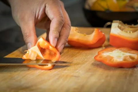 Chef cutting red bell pepper on wooden broad Fotos Stock