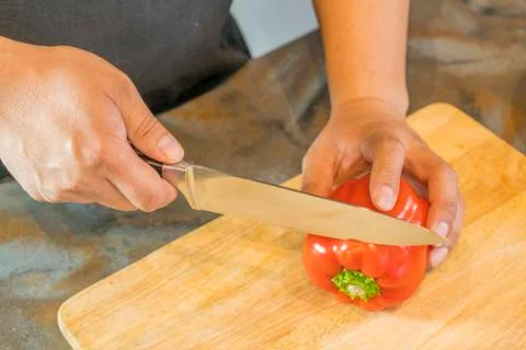Chef cutting red bell pepper on wooden broad Stockfoto's