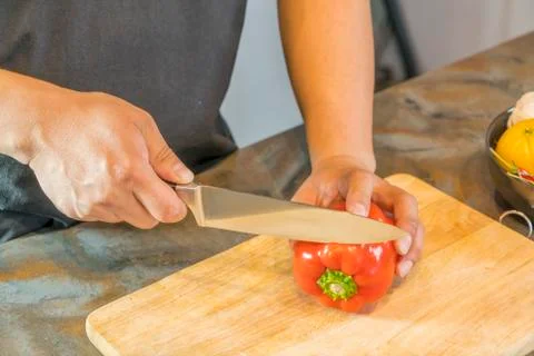 Chef cutting red bell pepper on wooden broad Фото