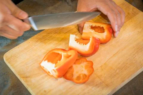 Chef cutting red bell pepper on wooden broad Stock-Fotos