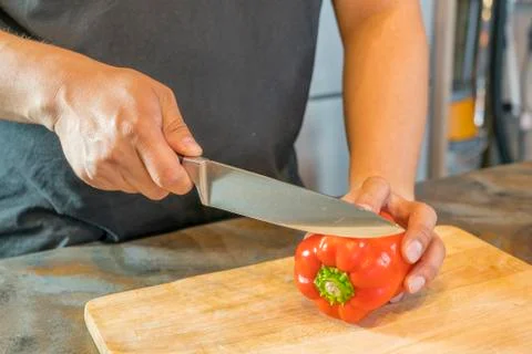 Chef cutting red bell pepper on wooden broad Stockfoto's