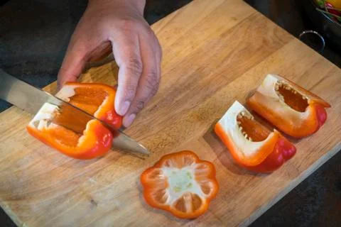 Chef cutting red bell pepper on wooden broad Stockfoto's