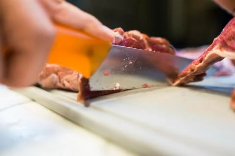 Chef cutting a slender piece of beef tenderloin with the background in blur Stock Photos