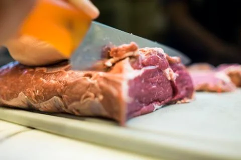 Chef cutting a slender piece of beef tenderloin with the background in blur Stock Photos