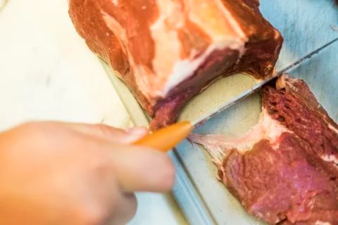 Chef cutting a slender piece of beef tenderloin with the background in blur Stock Photos