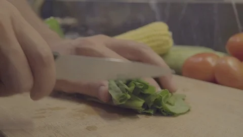 A chef cutting spinach on cutting board, vegetables on background Stock Footage 92846247