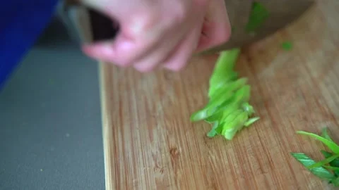 Chef cutting spring onion with the knife on the wooden board Stock Footage 158983514