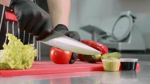 Chef is cutting tomato for burger, hands in black gloves closeup. Stock Footage 108332386