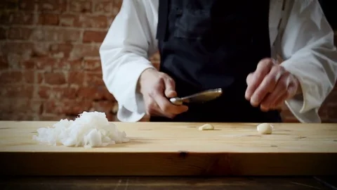 The chef cutting two cloves of garlic on chopping board for preparing food. 4K Vidéo 78421640