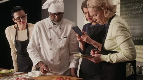 Chef Cutting Vegetables, Students Taking Photo and Writing Notes at Master Class Stockbeeldmateriaal 332571349