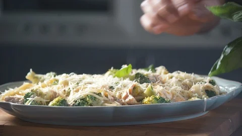 Chef decorates basil leaves with spaghetti pasta on plate in restaurant kitchen. 스톡 동영상 124711302