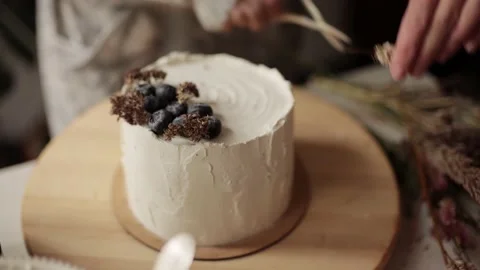 Chef decorates a cake with berries and dried flowers. Woman making cake at Stock Footage 143996720