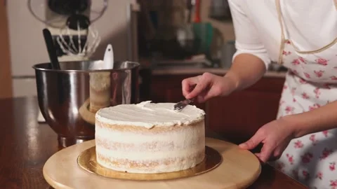 A chef decorates a cake with a spread of whipped cream. 4K footage Stock Footage 231504924