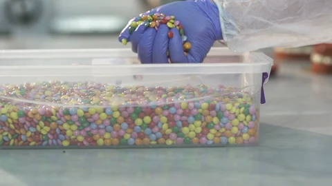 Chef decorates a cake using coated chocolate candies at bakery, slow motion Stock Footage 121962970
