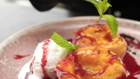 Chef decorates the dessert with mint, grilled peaches with ice cream and jam Stock Footage 160277666