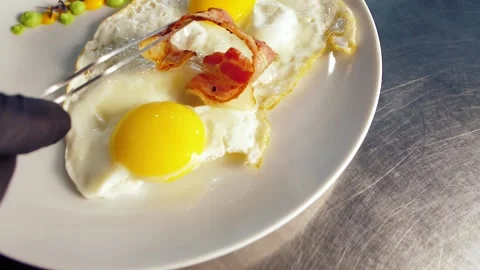 Chef decorates the dish with food, breakfast, fried egg, with tomatoes, bacon Stock Footage 149409109
