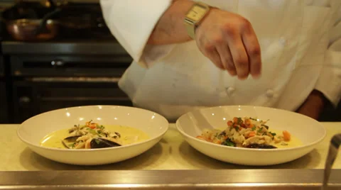 A chef decorates the food in the two plates in chef station Stock Footage 35406830