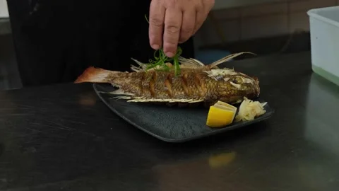 Chef decorates a plate of fried fish Stock Footage 155763257