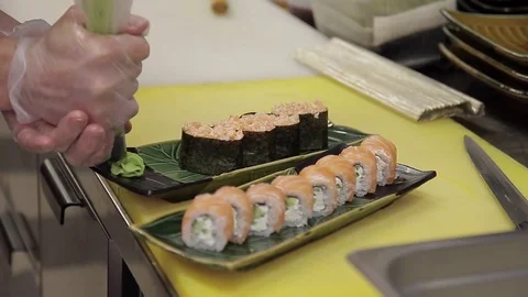 The chef decorates ready sushi rolls with wasabi in the restaurant kitchen Stock Footage 75679440