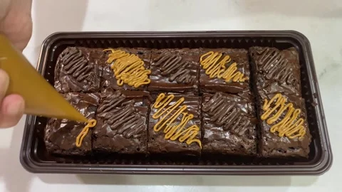 Chef decorating brownies with chocolate and caramel topping Video stock 271704836