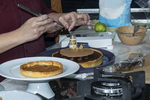 Chef decorating a chocolate pie with delicate gold leaf. Stock Photos