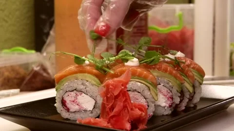 Chef decorating delicious sushi on black plate close-up Stock Footage 285251274