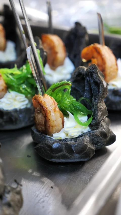 Chef decorating gourmet black tartlets with grilled shrimp and seaweed. Stock-Footage 341289932