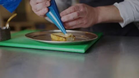 A chef is decorating a plate with a pastry Stock Footage 306577178
