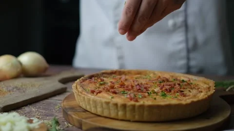 Chef decorating quiche by sprinkle topping on top. Stock Footage 132449792