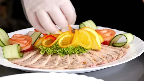A chef decorating sliced meat and chicken roulade dish, at a restaurant kitchen Stock Footage 98798045