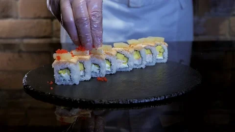 Chef is decorating sushi maki with flying fish roe, tobiko caviar Stock Footage 132828432