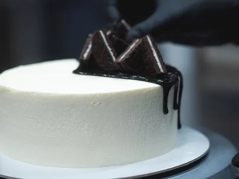 Chef decorating white icing drip cup cake with oreo cookies and dark chocolat Stock Photos
